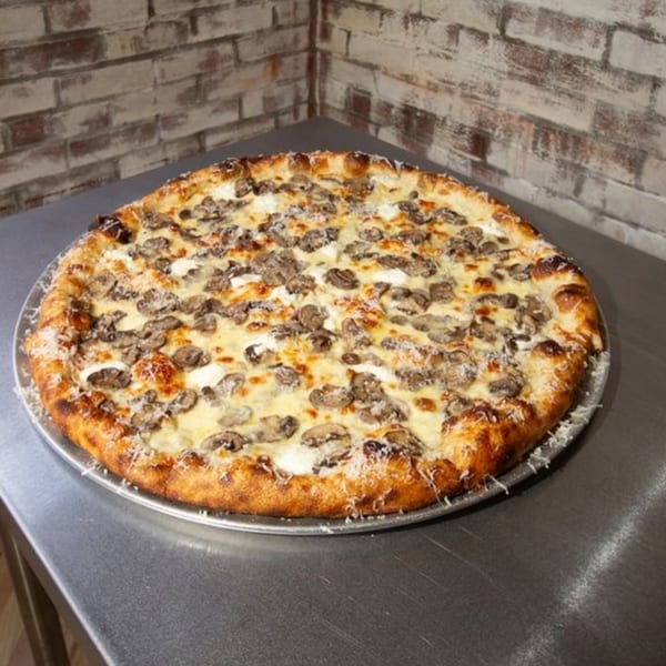 A Jonny's Pizza mushroom pizza with white sauce and parmesan cheese on a metal tray.